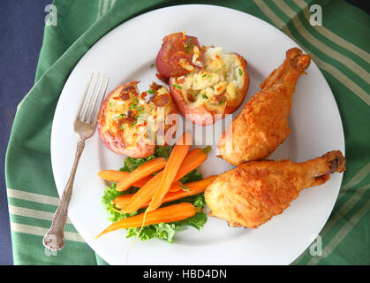 Fried chicken drumsticks with crushed potatoes and roasted carrots Stock Photo