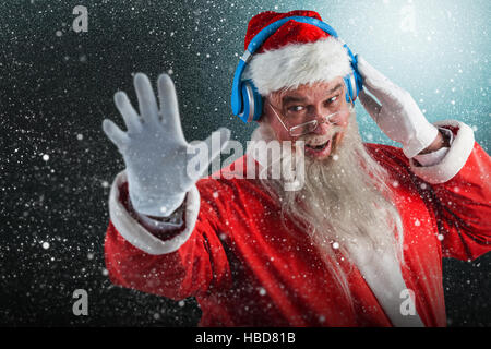Composite image of portrait of santa claus listening to music on headphones Stock Photo