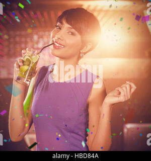 Composite image of young woman dancing on dance floor while having cocktail Stock Photo