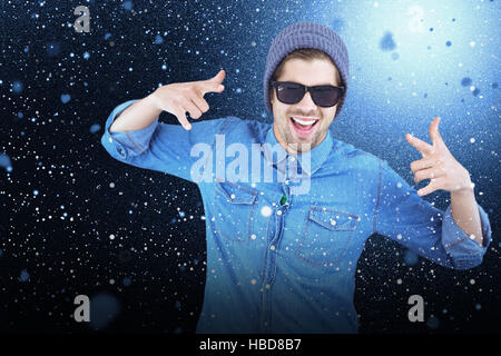 Composite image of happy hipster showing rock and roll hand sign Stock Photo