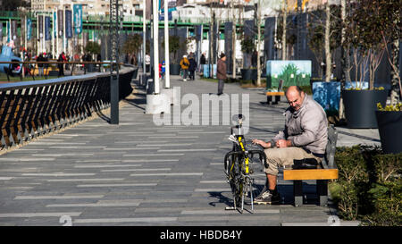 Belgrade, Serbia - A man sitting on a bench next to a broken bike Stock Photo