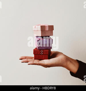 closeup of a young caucasian woman holding a balanced stack of small gifts in the palm of her hand Stock Photo