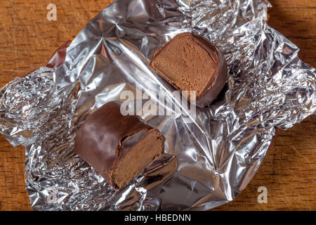 Cross section of one chocolate candy on silver foil over wooden background Stock Photo