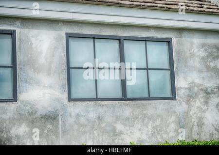 One window on the old brick wall covered with green leaves ivy plant Stock Photo