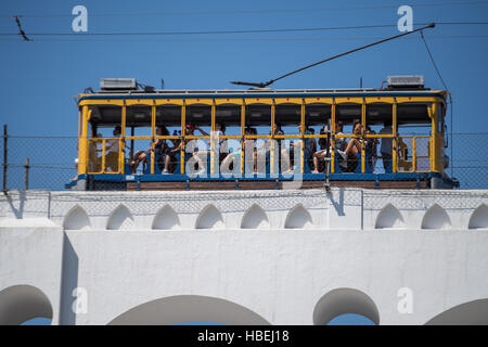 Tourists ride the Santa Teresa bonde historic tram line across the Carioca Aqueduct from the Santa Teresa neighborhood in Rio de Janeiro, Brazil. Stock Photo