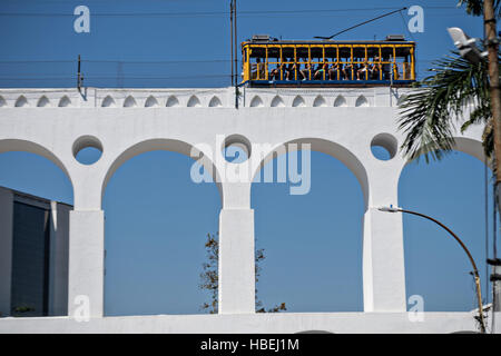 Tourists ride the Santa Teresa bonde historic tram line across the Carioca Aqueduct from the Santa Teresa neighborhood in Rio de Janeiro, Brazil. Stock Photo