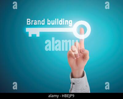 male hand pressing brand building key button over blue abstract background Stock Vector