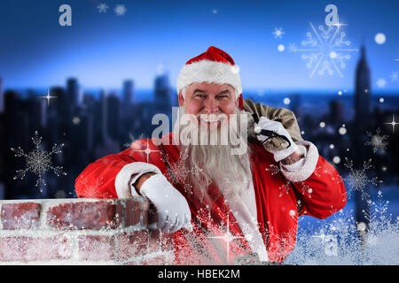 Composite image of portrait of santa claus carrying bag full of gifts Stock Photo