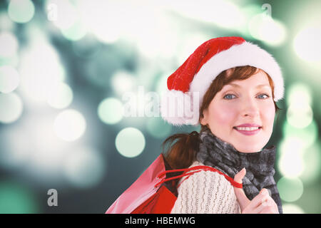 Composite image of smiling woman wearing santa hat Stock Photo