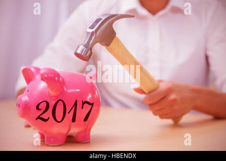 Composite image of man breaking piggy bank with hammer Stock Photo