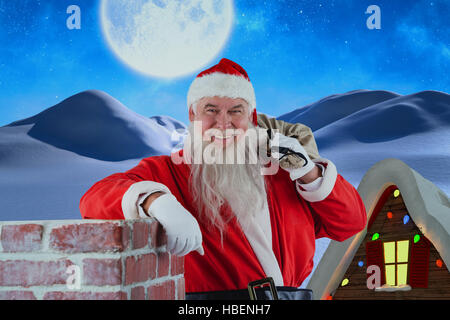 Composite image of portrait of santa claus carrying bag full of gifts Stock Photo