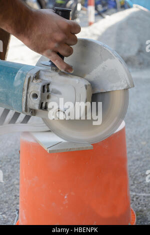 Skilled worker cuts tiles with angle grinder Stock Photo