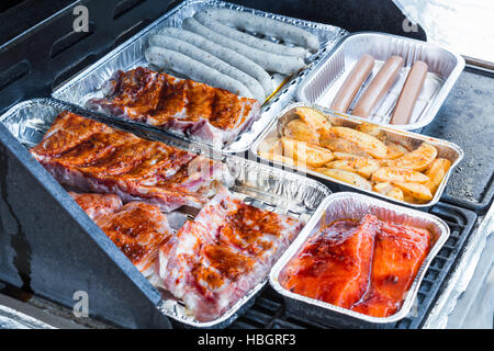 Meat and grill sausages on a gas grill. Stock Photo