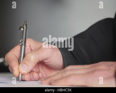 Close-up of man's hands writing with pen Stock Photo
