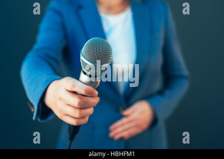 Elegant female journalist conducting business interview or press conference, hand with microphone Stock Photo