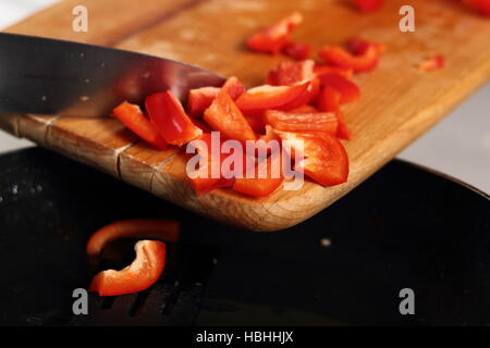 Adding sliced red bell pepper into frying pan. Making Chicken and Egg Galette Series. Stock Photo