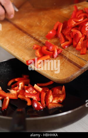 Adding sliced red bell pepper into frying pan. Making Chicken and Egg Galette Series. Stock Photo