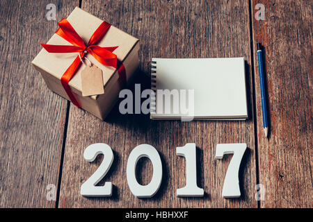 Wooden numbers forming the number 2017, For the new year 2017 on rustic wooden with gift box and red ribbon and notebook. Stock Photo