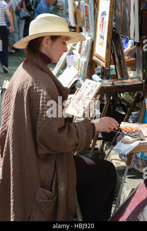 A female artist painting on canvas outdoors at Place du Tertre, Montmartre, Paris Stock Photo