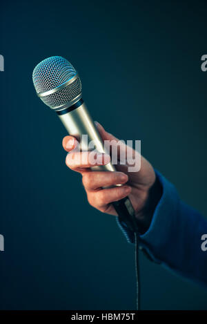 Elegant female journalist conducting business interview or press conference, hand with microphone Stock Photo