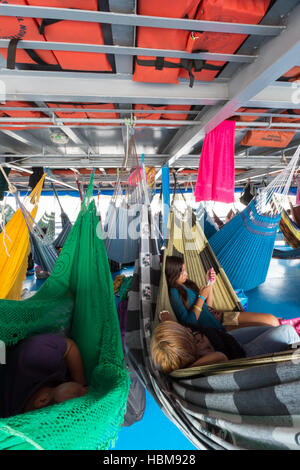 People resting in hammocks on passenger boat deck, Brazil Stock Photo