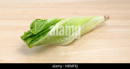 Head of romaine lettuce on a wood cutting board. Stock Photo