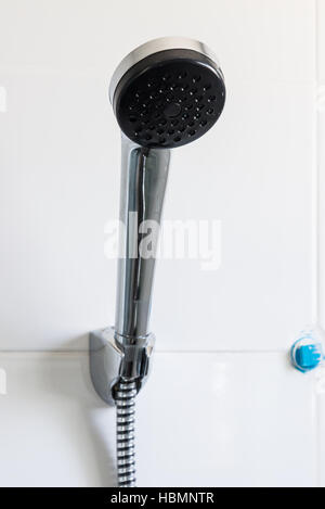 Old chrome shower is hanging on the white wall in the bathroom. Stock Photo