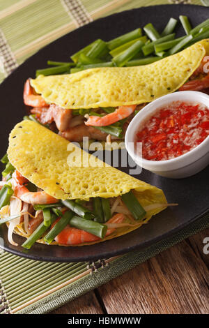 Vietnamese Banh Xeo crepes stuffed with pork, shrimp and bean sprouts and a spicy Nuoc Cham sauce closeup on a plate. Vertical Stock Photo