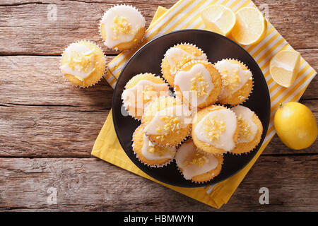 Homemade lemon muffins sprinkled with zest close-up on a plate on the table.  horizontal view from above Stock Photo