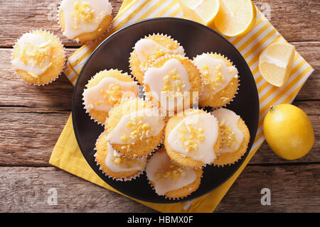 Sweet lemon muffins with zest and icing sugar close-up on a plate on the table.  Horizontal view from above Stock Photo