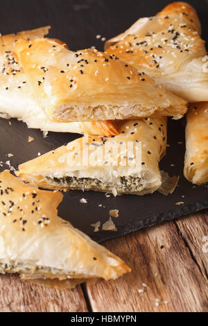 triangles of phyllo pastry stuffed with chicken, spinach and cheese close-up on the table. vertical Stock Photo