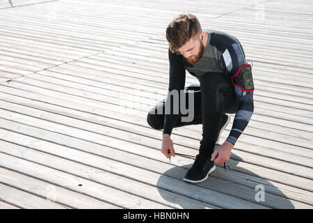 Top view of young runner preparing the sea. tying shoelaces Stock Photo