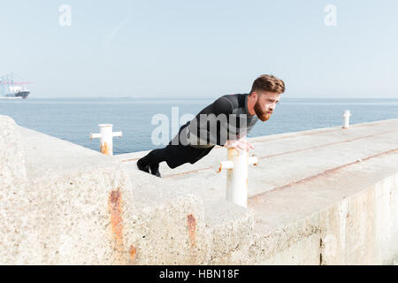 Man doing push ups near the sea. side view Stock Photo
