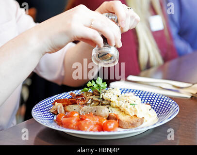 Cracked black pepper seasoning being added to a cooked breakfast at Carluccio Restaurant Stock Photo