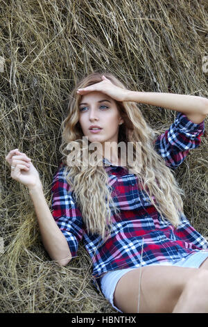 Young blonde country girl near haystacks Stock Photo