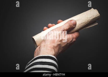 https://l450v.alamy.com/450v/hbntyh/strong-sailor-hand-holds-rolled-old-crumpled-paper-sheet-over-black-hbntyh.jpg