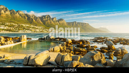 Camps Bay ocean pool at sunset with city and mountains behind Stock Photo