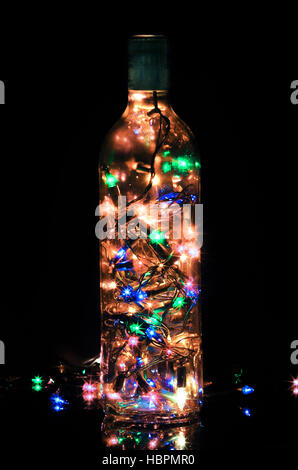 Glass bottle light with christmas yellow orange blue green pink lights over black background Stock Photo