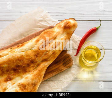 broken half pita bread caucasian, lying on a cutting board. Light wood background. Stock Photo