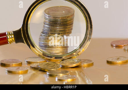 A stack of coins under a magnifying glass Stock Photo