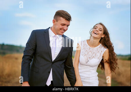 bride and groom walk in summer field Stock Photo