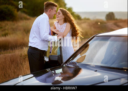 bride and groom kissing near car on wedding walk Stock Photo