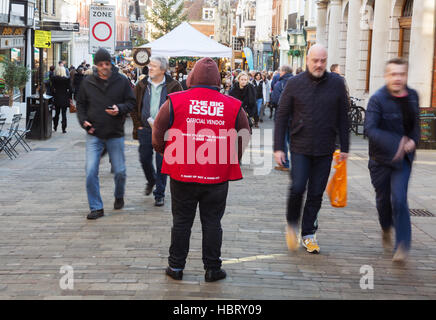 People walking past a Big Issue magazine vendor, Winchester, Hampshire, UK Stock Photo