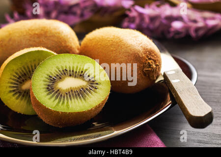 Kiwifruit served on plate on black wooden background Stock Photo