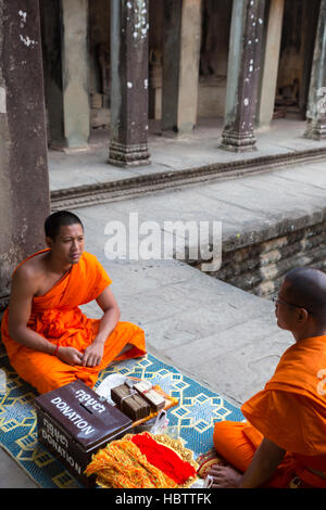 Cambodian monks sitting on stairs at Angkor Wat temple, Cambodia Stock Photo