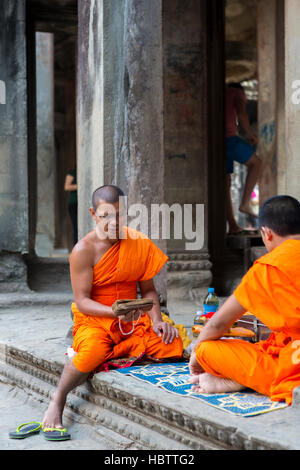 Cambodian monks sitting on stairs at Angkor Wat temple, Cambodia Stock Photo
