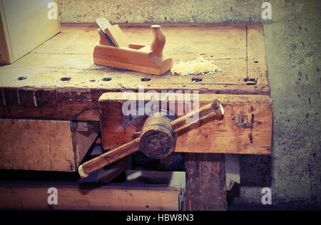 old wooden plane on the table of the workshop of carpenter with a wooden vise Stock Photo