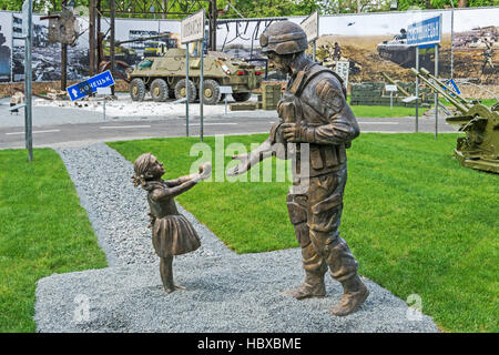 Dnepropetrovsk, Ukraine - May 19, 2016: Open air museum dedicated to war in the Donbass. Little girl has treated apple Ukrainian soldier Stock Photo