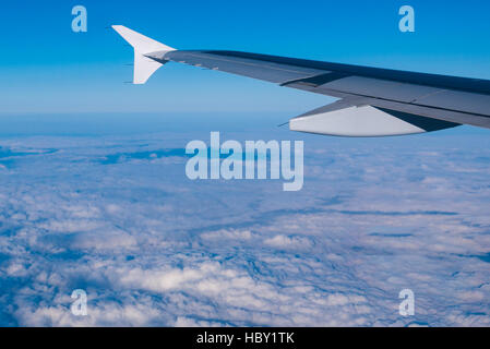 Wing of an airplane flying above the clouds Stock Photo