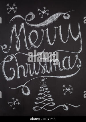Merry Christmas hand drawn lettering with chalk on blackboard. Elegant unique design with snowflakes and Christmas tree Stock Photo